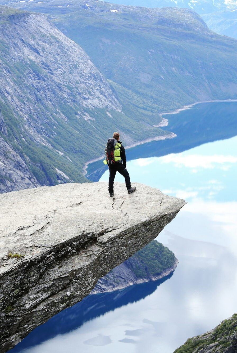 Man standing on the edge of Trolltunga cliff in Norway