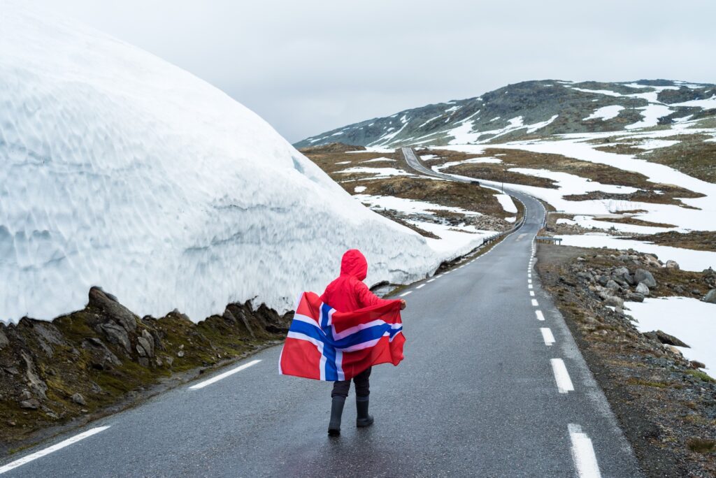 Girl with a Norwegian flag on a mountain road in Norway